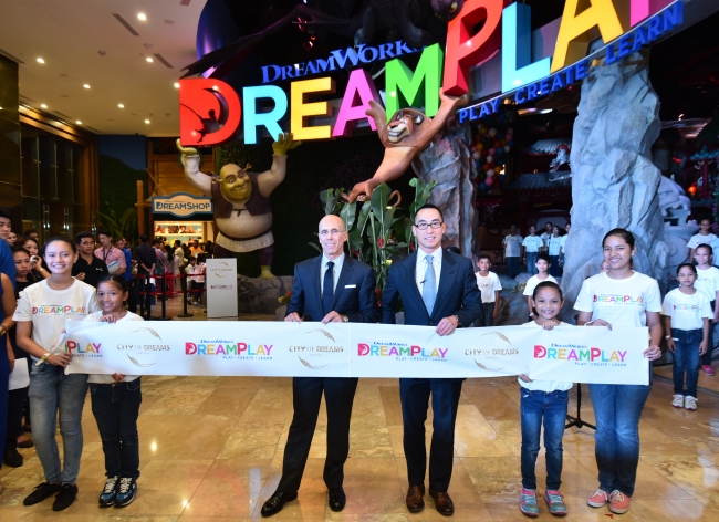 「DreamPlay by DreamWorks」のオープニング式典で、マンダルヨン子供合唱団の少年少女たちと並ぶ（左から）ドリームワークス・アニメーション最高経営責任者ジェフリー・カッツェンバーグならびにメルコ・クラウン・エンターテインメント共同会長兼CEOのローレンス・ホー