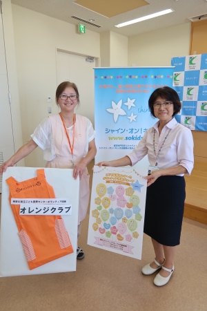 ボランティアコーディネーター 加藤悦與氏の手にはオレンジクラブの活動グループの一覧が。右上の星に新しく「ベイリー」を追加していただきました。