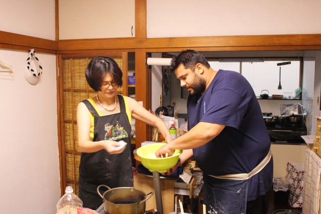 東京在住のホスト（左）宅で天ぷらうどんを一緒に作るオーストラリアからの旅行者のダニエルさん(右)