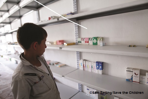 父親が経営する薬局の、ほぼ空になった 商品棚を見つめる子ども