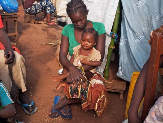 © UNICEF/NYHQ2013-1158/Mia Farrow　避難所のテントの外で子どもを抱く母親