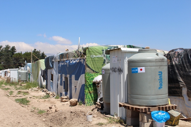日本政府支援による貯水タンク、隣にあるのはトイレ、ビニールシートに覆われているのがシリア難民の住居©UNICEF Lebanon/2014