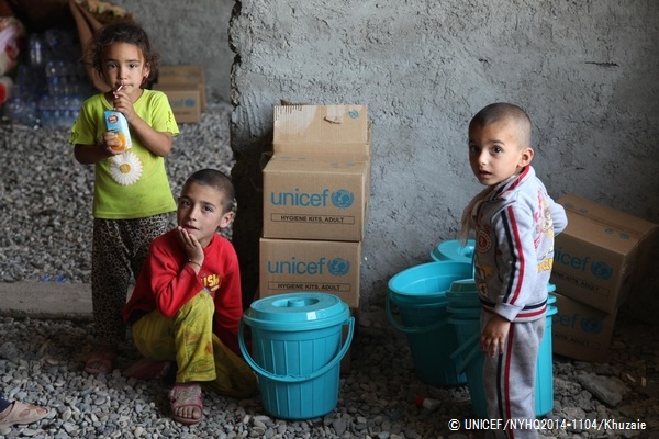 ユニセフが配布した衛生用品の詰め合わせやバケツと、避難している子どもたち。© UNICEF/NYHQ2014-1104/Khuzaie