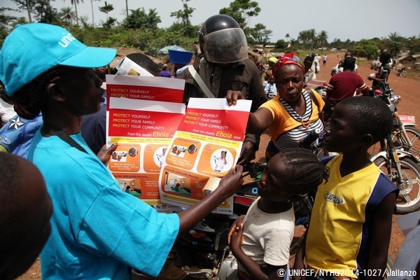 エボラに感染した際の対処法が載ったポスターを配るスタッフ。© UNICEF/UNI167513/Jallanzo
