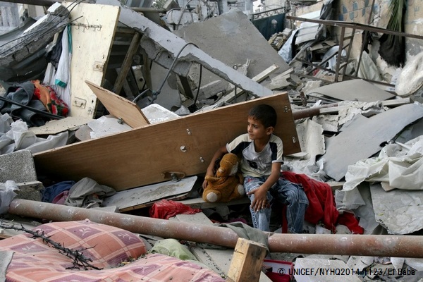 瓦礫の中で、おもちゃを片手に座る男の子。© UNICEF/NYHQ2014-1123/El Baba