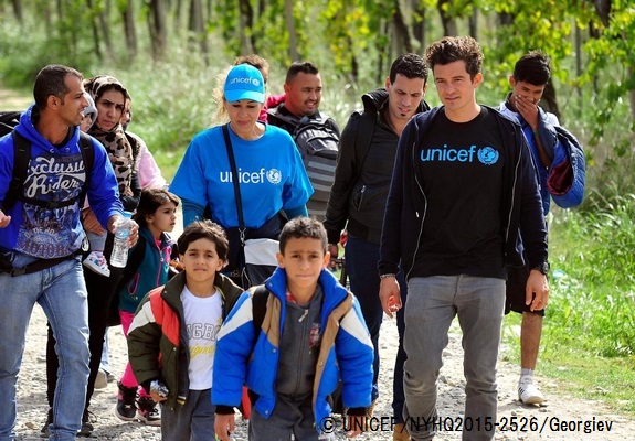 9月29日、マケドニア旧ユーゴスラビア共和国のゲヴゲリヤの一時受け入れ所近くで、子どもたちと一緒に歩くオーランド・ブルーム親善大使。© UNICEF_NYHQ2015-2526_Georgiev