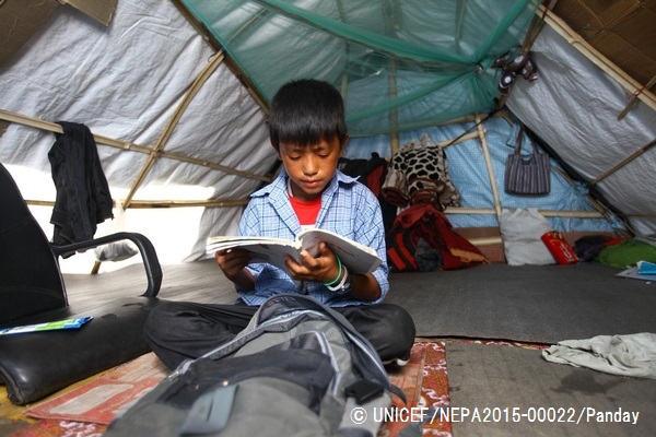 仮設テントの中で本を読む男の子。© UNICEF_NEPA2015-00022_Panday