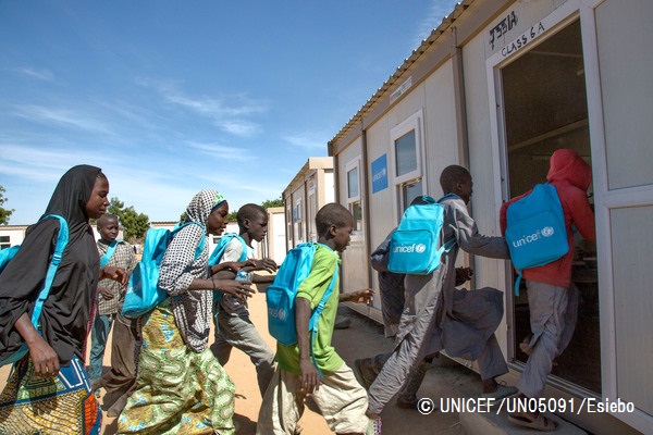 国内避難民キャンプにある学校で、ユニセフの支援物資の通学かばんを身につけて教室に入る子どもたち。© UNICEF_UN05091_Esiebo