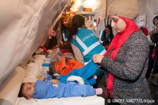 ユニセフの支援物資配給所で受け取った赤ちゃん用の暖かい服を着せる女性。（クロアチア）© UNICEF_UN07723_Kljajo