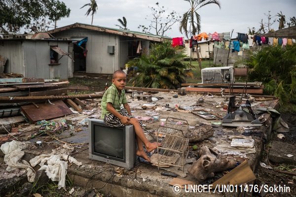 サイクロンで破壊された自宅に残されたテレビの上に座る7歳の男の子。© UNICEF_UN011476_Sokhin