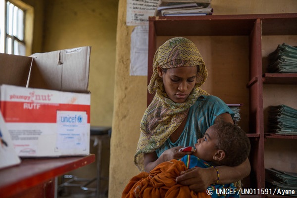 すぐ口にすることができる栄養補助食を2歳の息子に食べさせる母親。© UNICEF_UN011591_Ayene