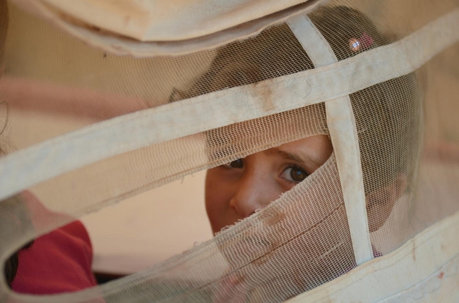 トルコとの国境付近のアトマに設置された国内避難民を収容するキャンプで、テントの隙間からこちらの様子を伺う女の子(シリア） ©UNICEF/NYHQ2013-0494/JOHN WREFORD 
