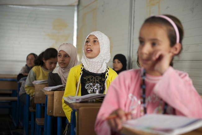 ヨルダン北部にあるザータリ難民キャンプ内に設置せれた仮設の学校で先生の質問にこたえるザイナブちゃん（11歳）(c) UNICEF/NYHQ2013-0561/SHEHZAD NOORANI