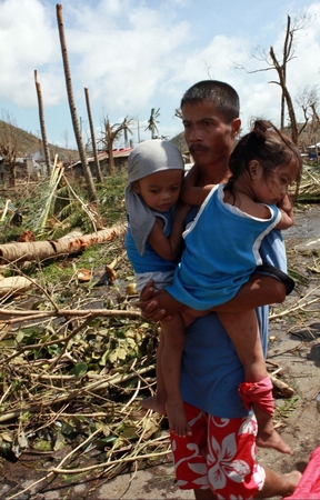 © UNICEF/NYHQ2013-0991/Maitem 台風が上陸したタクロバン市内で 2人の子どもを抱える男性。