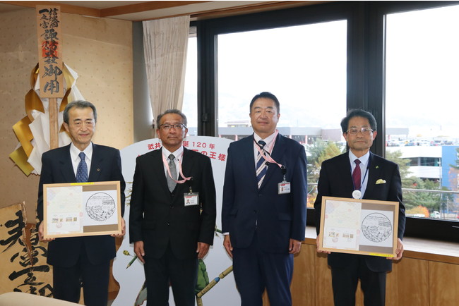 岡谷郵便局青木修一局長（左から二人目）より今井竜五市長（左）へ風景印と記念台紙が贈呈された