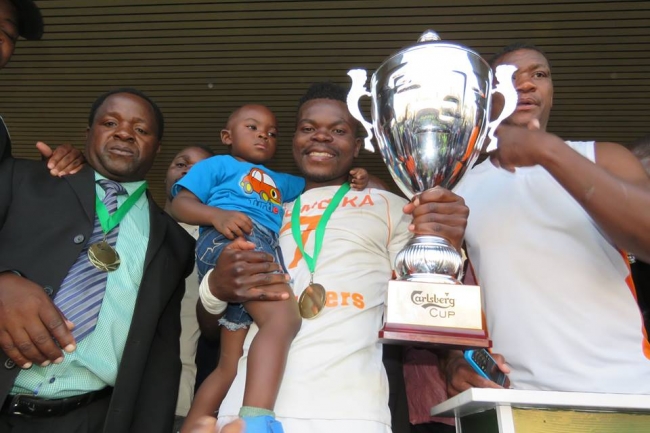 息子と優勝カップを抱くキャプテンのフランシス・ムリンビカ