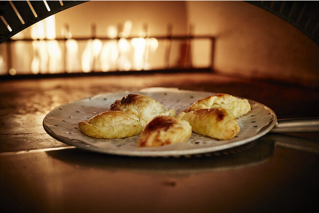 クリーミーなシーフードグラタンをパイ生地で包み、石窯で焼き上げる「シーフードクリームのカルツォーネ」。ブルギニオンバターの芳醇な香りがアクセントに。