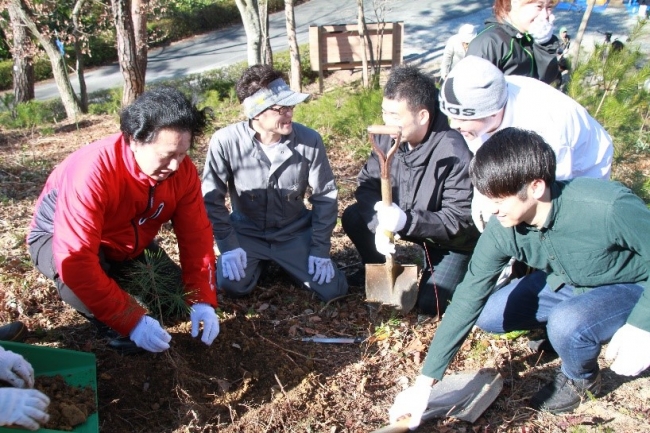 社員と植樹をする社長の津村（写真左）