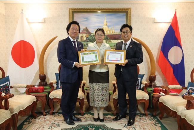 同国政府より感謝状を受け取る当社社長の津村佳宏(写真左)とフォンサムット・アンラワン特命全権大使(写真中央)、アデランス・ラオス社会長の千藤伸一(写真右) 同国政府より感謝状を受け取る当社社長の津村佳宏(写真左)とフォンサムット・アンラワン特命全権大使(写真中央)、アデランス・ラオス社会長の千藤伸一(写真右)