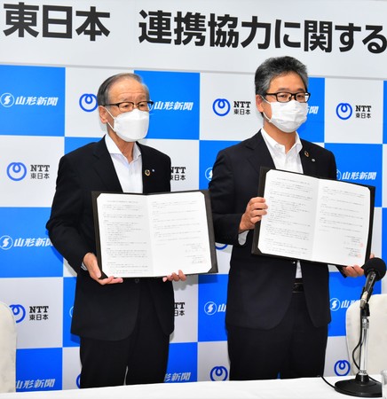 協定書を手に写真に納まる寒河江浩二山形新聞社長（左）と渡会俊輔NTT東日本山形支店長＝山形市・山形グランドホテル