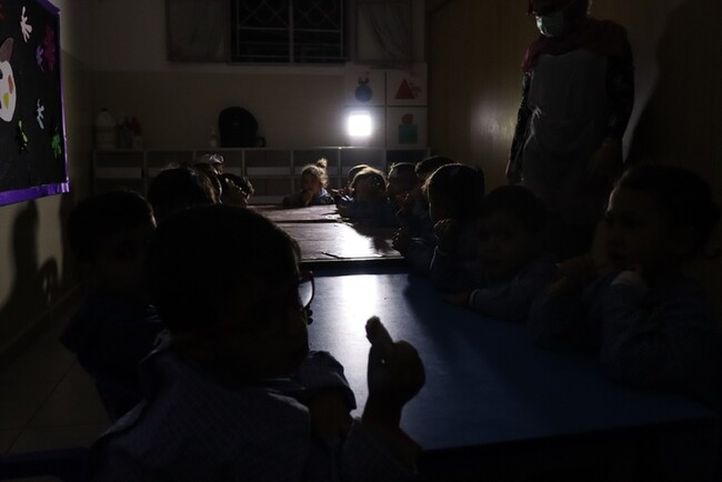 幼稚園。停電が続き、小さなライトの明かりで給食を食べる園児たち