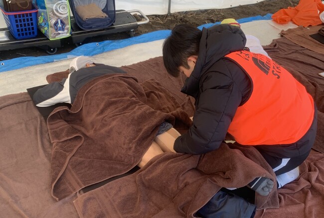 大会中に肉離れをしてしまったランナーにテーピングをしている写真 大会中に肉離れをしてしまったランナーにテーピングをしている写真