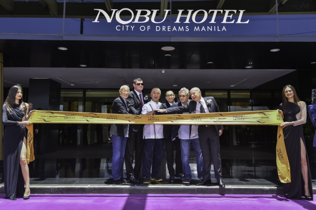 テープカットにより、シティ・オブ・ドリームス・マニラにアジア初となるノブ・ホテルが正式にオープン。日本式の短刀を持つのは、（左から）ハリウッド・プロデューサーでノブのパートナーのメイア・テペル、メルコ・クラウン共同会長ジェームス・パッカー、松久信幸シェフ、メルコ・クラウン・エンターテインメント共同会長兼CEOローレンス・ホー、アカデミー賞受賞俳優でノブのパートナー、ロバート・デ・ニーロとノブ・ホスピタリティー最高経営責任者のトレバー・ホーウェル