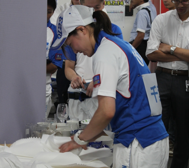 「小物梱包」競技で手際よく食器を包む参加者