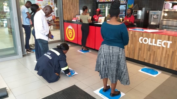 ザンビアの店舗の床に貼られた人との距離を保つためのステッカー（WatrAid Zambia）