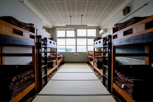 旧教室に２段ベッドが並ぶ大部屋