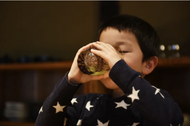 画像の説明：お子様が両手でグラスをもって飲み物を飲んでいる様子