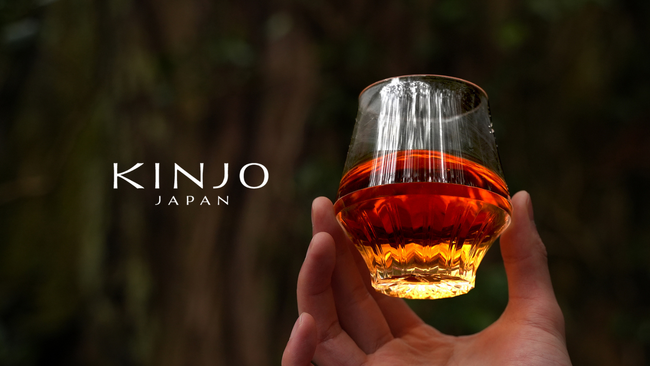 画像の説明：森を背景に、香りの良いお酒の入ったKINJO JAPAN F0を高く持っている様子と左にブランドロゴが掲載されている