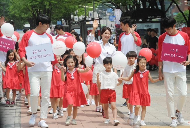 【韓国】赤と白の風船を持ったこども達がソウル市内の繁華街江南を行進