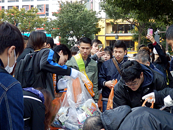 早朝から地元の人と一緒にごみ拾いを手伝う日本経済大学の学生たち。