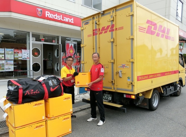 DHLジャパンの配送スタッフに、ミャンマー向け支援物資を手渡す浦和レッズハートフルクラブの落合キャプテン