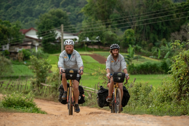 ラオス国内を自転車で疾走するロン・ルトランド（左）と、ジェームス・オーウェン（右）