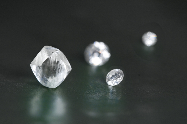 手前（左）カット・研磨前の天然ダイヤモンドと（右）グランバーガープレシジョンカット®完成品メレダイヤモンド（従来の58面カット）