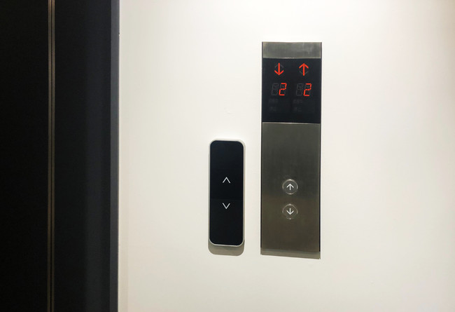 新設の非接触エレベーター操作盤（左）。 既存のエレベーターに追加設置した。