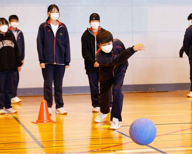 パス練習では、7人ずつのグループに分かれ、ボールを投げ合います。身体を大きく使ったり、股の間から投げてみたり、自分なりの投げ方を試している生徒もいました。