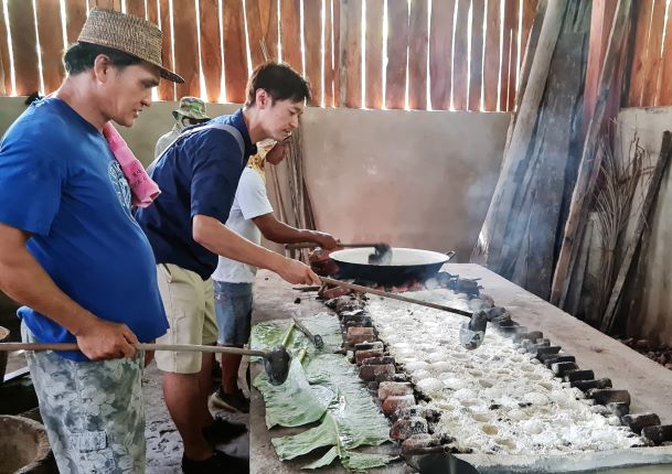 ボホール島で伝統的な塩の製法を体験する川手シェフ。  ココナッツ殻の灰に海水を注いで作る。  
