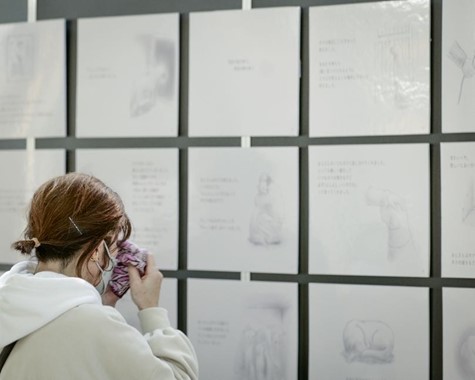 ハンカチを手に、作・絵 kaiseiさんの「ある犬のおはなし〜殺処分ゼロを願って〜」の展示を見つめる来場者 ハンカチを手に、作・絵 kaiseiさんの「ある犬のおはなし〜殺処分ゼロを願って〜」の展示を見つめる来場者