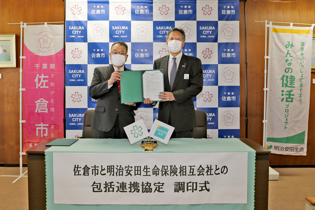 署名済みの協定書を掲げる西田佐倉市長（左）と明治安田生命金山理事・千葉本部長（右）
