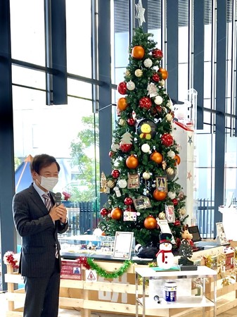 クリスマスツリーの前で子どもたちに語りかける宮原博昭社長