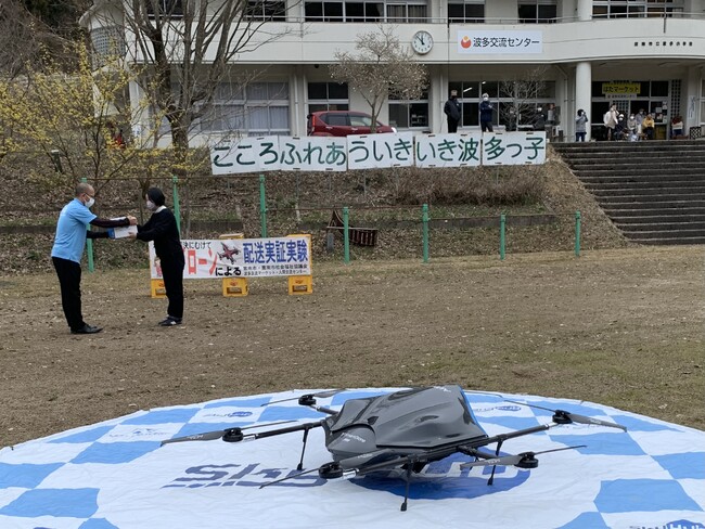 おでんと焼鯖弁当の入ったドローン用の箱を受け取るスタッフ おでんと焼鯖弁当の入ったドローン用の箱を受け取るスタッフ