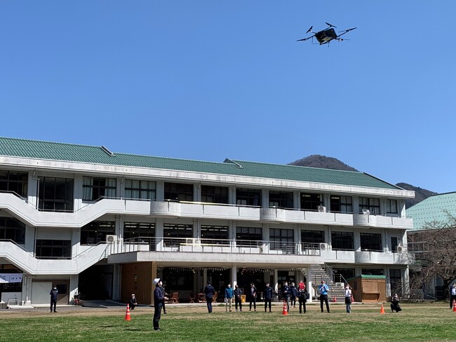 共同配送の荷物と隼Lab.内Sanのサンドイッチとドリンクを載せて離陸する物流専用ドローン”AirTruck” (隼Lab.前グラウンド) 共同配送の荷物と隼Lab.内Sanのサンドイッチとドリンクを載せて離陸する物流専用ドローン”AirTruck” (隼Lab.前グラウンド)