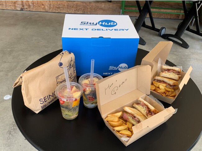 ドローン配送された共同配送の荷物と隼Lab.内Sanのサンドイッチとドリンク ドローン配送された共同配送の荷物と隼Lab.内Sanのサンドイッチとドリンク