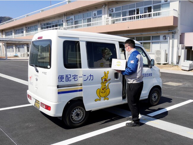 ドローン配送されたサイクリストのお土産の入った箱を車に積み替えリレー配送 (神川町多目的交流施設の駐車場) ドローン配送されたサイクリストのお土産の入った箱を車に積み替えリレー配送 (神川町多目的交流施設の駐車場)