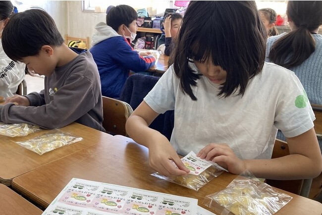 梅林小学校の4年生と共同開発「うめぇはちみつあめ」　仕上げのラベルも児童が丁寧に貼りました