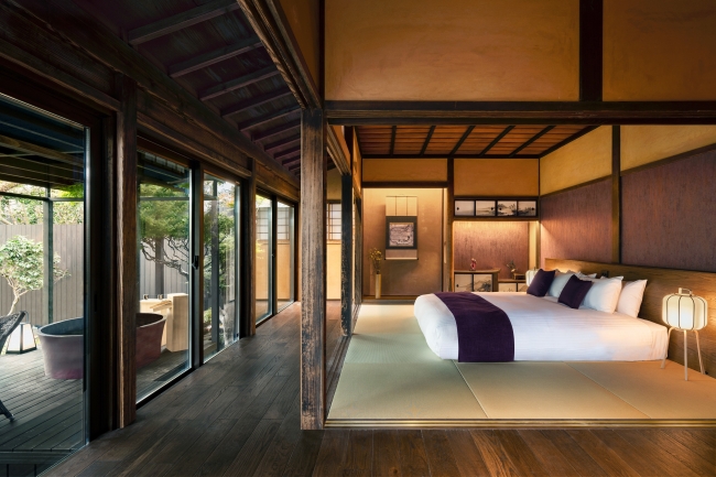 客室「HONMURASAKI」 飫肥の町の⾊である紫を基調とした寝室と温泉露天⾵呂
