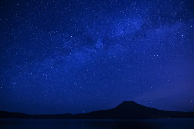 阿寒湖上にきらめく満天の星と雄阿寒岳（イメージ）